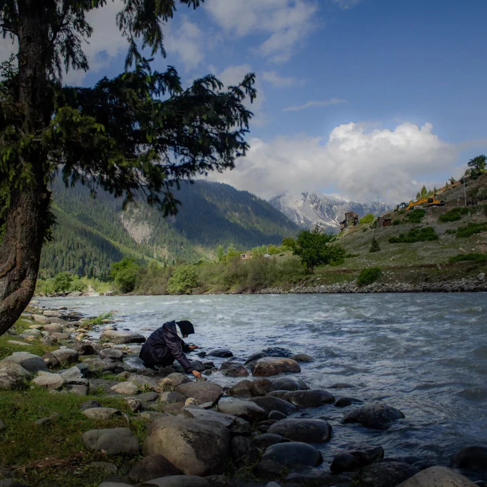A river flowing through a green mountain valley, photographed by Nawaar.