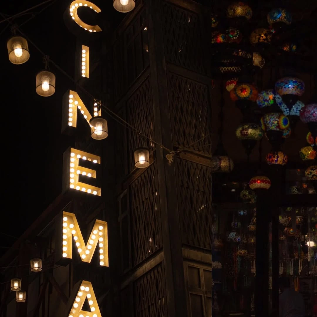 Illuminated cinema lettering and hanging lamps at night.