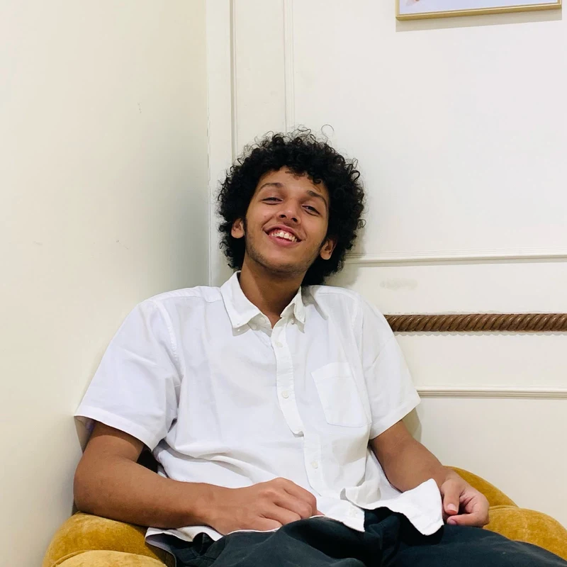Nawaar smiling, seated in a white shirt.